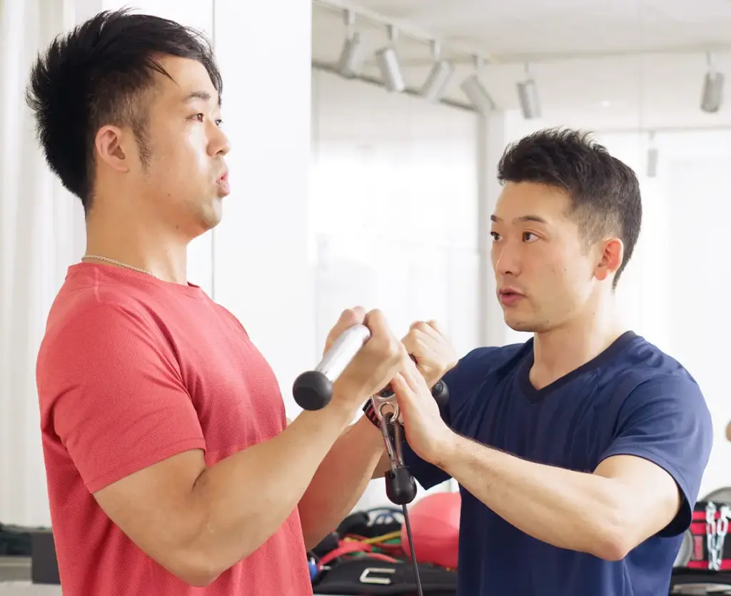 ケーブルアームカールを使ってトレーニングを男性と、トレーナー